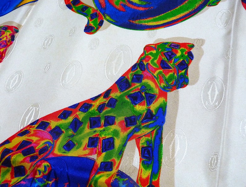 May include: A white fabric with a repeating pattern of a stylized 'C' in a circle. The fabric also features a colorful cheetah print with red, yellow, blue, and green colors.
