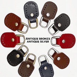 May include: A selection of leather bag bases in shades of red, brown, black, and navy. Each base features a metal D-ring and a metal rivet. The text "ANTIQUE BRONZE ANTIQUE SILVER" is displayed. These are ideal for crafting.