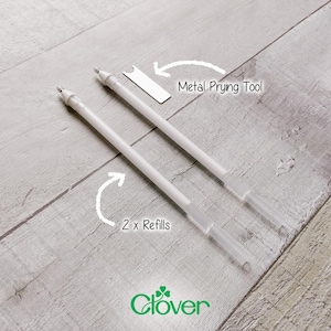 May include: Two white Clover brand refill pens with clear tips and a metal prying tool are displayed on a light grey wooden surface. The text "2 x Refills" and "Metal Prying Tool" are indicated with arrows.