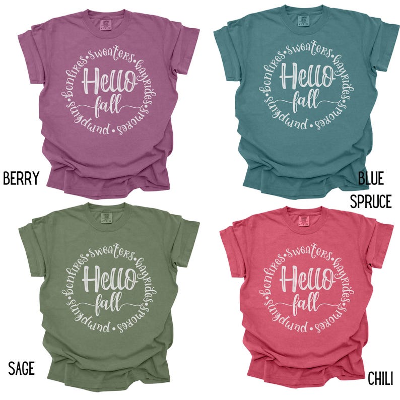 May include: Four different colored t-shirts with a white circle graphic that says "Hello Fall" with the words "bonfires, sweaters, hayrides, smores, pumpkin" surrounding the text.