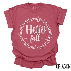May include: A crimson red t-shirt with a white circle graphic that says "Hello Fall" surrounded by the words "bonfires, sweaters, hayrides, smores, sundowns".