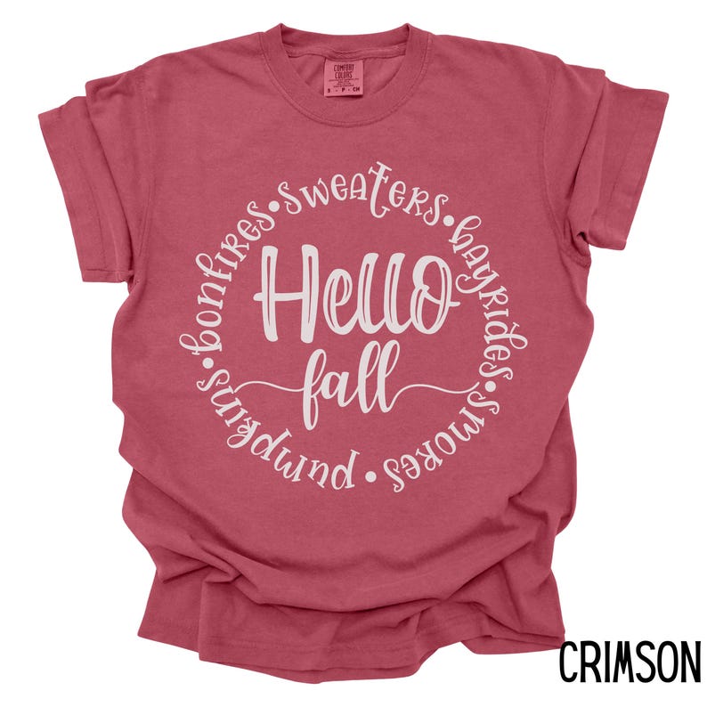May include: A crimson red t-shirt with a white circle graphic that says "Hello Fall" surrounded by the words "bonfires, sweaters, hayrides, smores, sundowns".