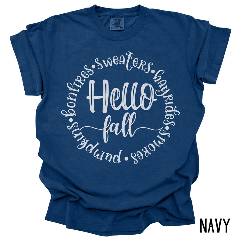 May include: A navy blue t-shirt with a white circle graphic that says "Hello Fall" surrounded by the words "bonfires, sweaters, hayrides, s'mores, pumpkin".
