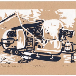 May include: A black and white linocut print of a vintage Airstream trailer with an awning extended. The print is titled "Airstream" and signed "Sarah Whyte" with the number "4/5" in the bottom right corner.