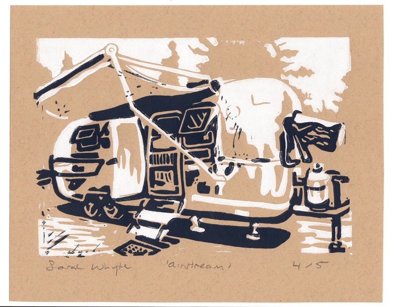 May include: A black and white linocut print of a vintage Airstream trailer with an awning extended. The print is titled "Airstream" and signed "Sarah Whyte" with the number "4/5" in the bottom right corner.