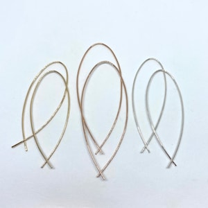 May include: Three pairs of delicate, thin, oval-shaped hoop earrings in gold, rose gold, and silver.