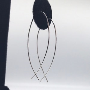 May include: A pair of silver hoop earrings with a curved, fish-like shape.