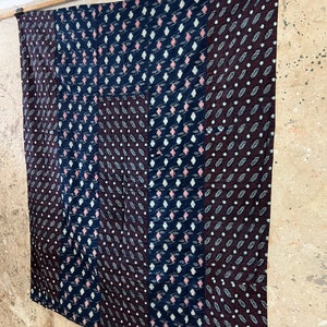 May include: A patchwork quilt with a geometric pattern in shades of blue, black, and pink. The quilt is made of different fabrics with a variety of textures.