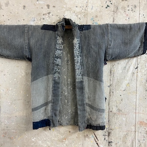 Puede incluir: Chaqueta japonesa vintage teñida con añil, con diseño de patchwork y costuras visibles. La chaqueta tiene caracteres japoneses impresos en la parte delantera. Las mangas son anchas y la chaqueta está abierta. La tela muestra desgaste.