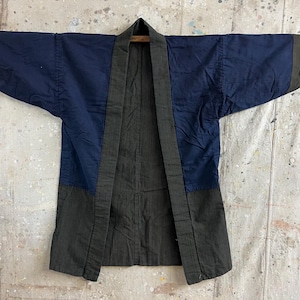 Puede incluir: Chaqueta vintage de dos tonos con frente abierto. La parte superior es azul marino, mientras que la sección inferior y los ribetes son de color verde oliva oscuro. La chaqueta se muestra plana, destacando su diseño y construcción.