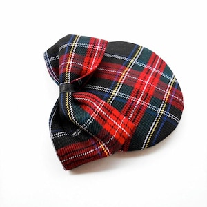 May include: A plaid bow tie in red, green, black, and yellow. The bow tie is made of a woven fabric and has a black leather band. The bow tie is a classic accessory.