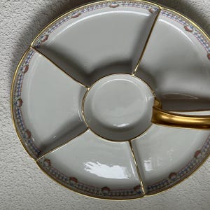 May include: A white divided serving platter with a gold handle and trim. The platter is divided into six sections, with a small round center section. The rim features a blue, red, and gold floral pattern.