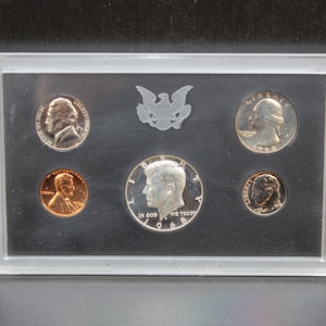 May include: A clear plastic case containing a 1968 proof set of US coins. The set includes a half dollar, quarter, dime, nickel, and penny.