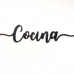 以下が含まれることがあります： 「Cocina」と cursive で書かれた黒い木製の看板です。