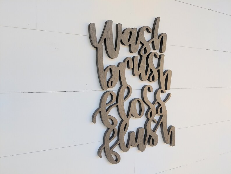May include: Wooden sign with the words "Wash, Brush, Floss, Flush" in a cursive font.