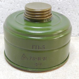 Op de afbeelding: Een groene gasmaskerfilter met een schroefdraad bovenop en een cilindrisch lichaam. De filter heeft tekst en symbolen op de zijkant, waaronder "ГП-5" en andere markeringen.
