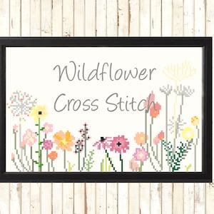 May include: Framed cross-stitch art featuring a colorful wildflower design. The artwork includes various pixelated flowers in shades of pink, yellow, orange, and green, with the words "Wildflower Cross Stitch" in gray text.