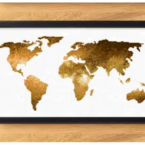 May include: A framed world map cross-stitch art piece. The map is rendered in shades of gold and brown against a white background, with a black frame. The artwork is displayed on a wooden surface.
