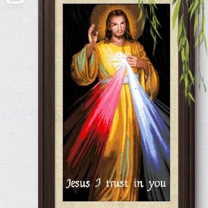 Puede incluir: Obra de arte religiosa enmarcada que representa a Jesús con un halo dorado y vestiduras. La imagen muestra rayos de luz roja, rosa y azul que emanan de su pecho. El texto "Jesus I trust in you" está en la parte inferior.