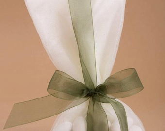 Puede incluir: Una bolsa de organza blanca con una cinta de satén verde atada en un lazo. La bolsa está llena de almendras confitadas blancas.