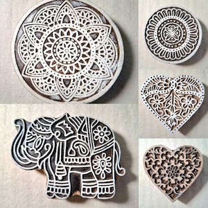 May include: Five wooden printing blocks with intricate designs. The designs include a mandala, a heart, an elephant, and two more hearts. The blocks are made of light brown wood and have a white design.