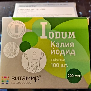 Pode incluir: Uma caixa verde e branca de comprimidos de iodeto de potássio, rotulada "IODUM Kalya yodiD" com uma imagem da glândula tireoide e o texto "100 шт. 200 мкг".