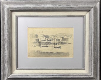 May include: A framed black and white pencil drawing of a harbor scene with boats and buildings. The drawing is in a simple wooden frame.