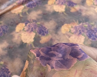 May include: A sheer fabric with a floral print featuring purple and orange flowers on a brown background.