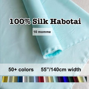 May include: A roll of light blue 100% Silk Habotai fabric. The image shows the fabric rolled up and spread out, with the text "100% Silk Habotai", "10 momme", "50+ colors", and "55"/140cm width". A variety of colour swatches are shown at the bottom.