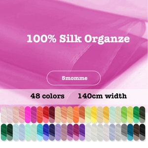 Könnte beinhalten: Nahaufnahme eines rosa 100% Seidenorganza-Stoffes mit dem aufgedruckten Text "100% Silk Organza" und "5momme". Der Stoff ist 140 cm breit und in 48 Farben erhältlich. Ein Stoffmuster ist in 48 verschiedenen Farben dargestellt.