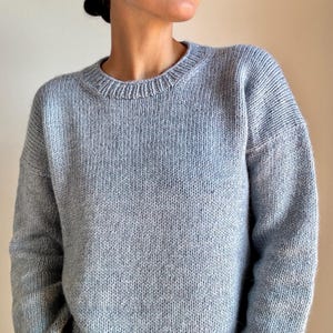 May include: A light blue knitted sweater with a crew neck.