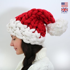 May include: A red and white knitted Santa hat with a white pom-pom. The hat is made of chunky yarn and has a wide brim.