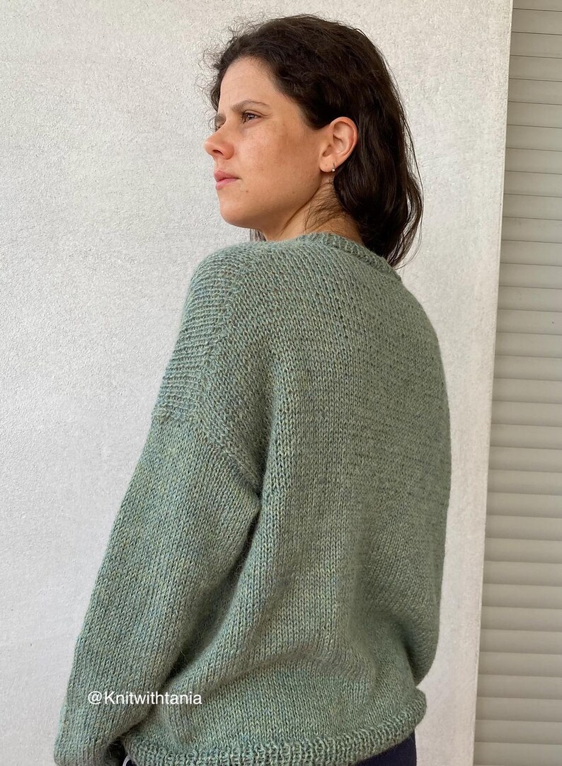 May include: A soft, green knitted sweater with a crew neck. The sweater is made with a textured stitch and has a relaxed fit.