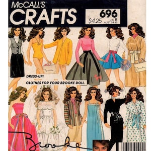 May include: A vintage McCall's Crafts pattern for making clothes for a Brooke doll. The pattern cover features illustrations of a doll wearing various outfits, including a yellow swimsuit, a black skirt, a blue dress, and a white wedding dress. The text on the cover reads "Dress-Up! Clothes for your Brooke doll."
