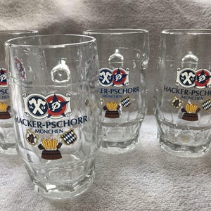 May include: Four clear glass beer steins with a white and blue logo that says "Hacker-Pschorr Munchen".
