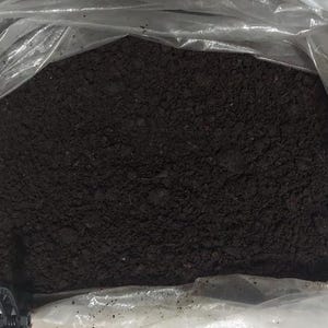May include: A close-up of a bag of dark brown soil. The soil is loose and appears to be ready for planting.