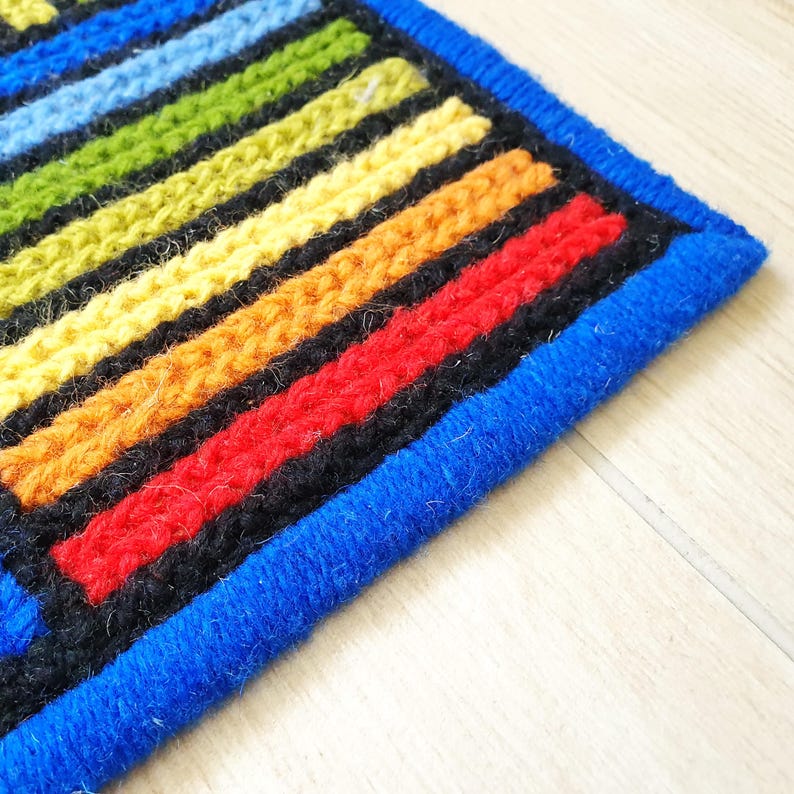 Detailed texture of thick wool yarn embroidered on a natural jute base.