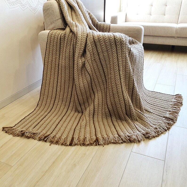 Soft crochet wool throw with neutral color palette and dense knit structure, the throw blanket is drapped over a chair.
