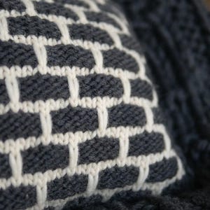 Close up of chunky knit wool texture. Natural breathable fiber cushion cover in white and black yarn for cozy home.