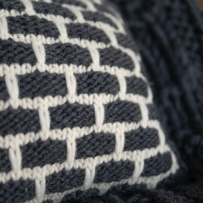Close up of chunky knit wool texture. Natural breathable fiber cushion cover in white and black yarn for cozy home.