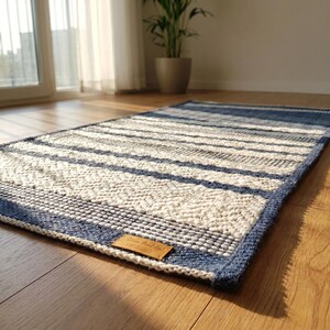 Cotton woven rug placed on floor, minimal interior setting with natural light.