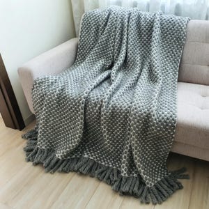 Handmade chunky wool blanket in gray tones used as a sofa throw in a modern interior