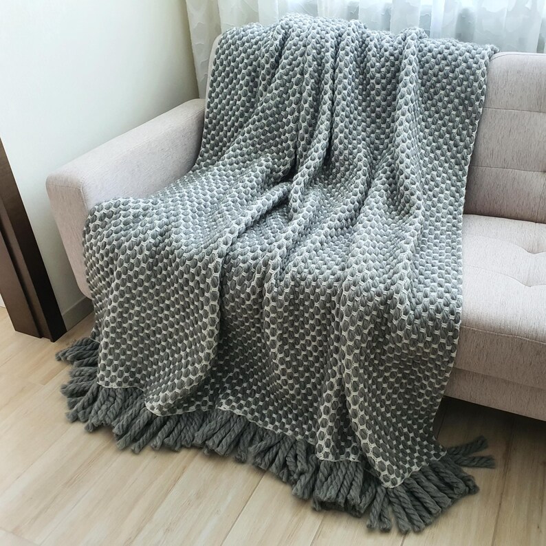 Handmade chunky wool blanket in gray tones used as a sofa throw in a modern interior