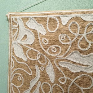 Close-up of wool embroidery showing dense stitches and organic curved leaf forms