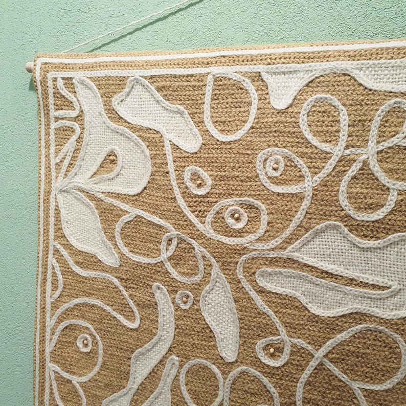 Close-up of wool embroidery showing dense stitches and organic curved leaf forms