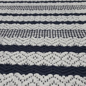 Detailed view of blue and white cotton rug showing stitch variation and density.