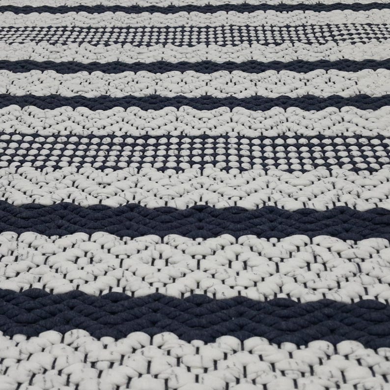Detailed view of blue and white cotton rug showing stitch variation and density.