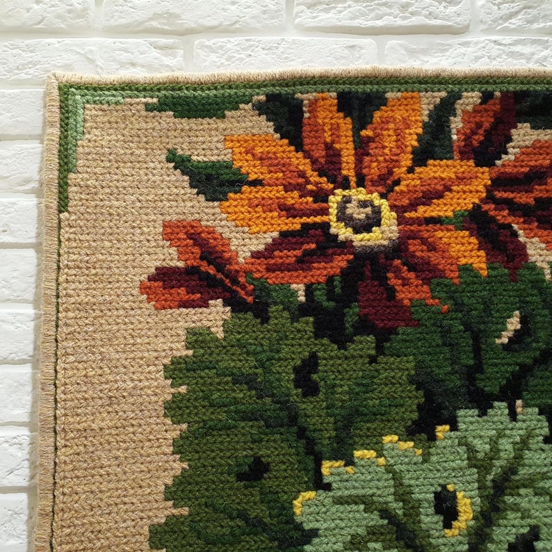 Close-up of wool embroidered panel with floral design, visible stitches and textured surface