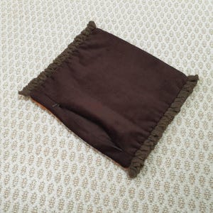 Puede incluir: Una funda de almohada marr&oacute;n con un borde texturizado y con flecos. La funda de almohada tiene una cremallera oculta y est&aacute; hecha de una tela marr&oacute;n oscuro lisa. El borde con flecos es de un tono marr&oacute;n m&aacute;s oscuro.