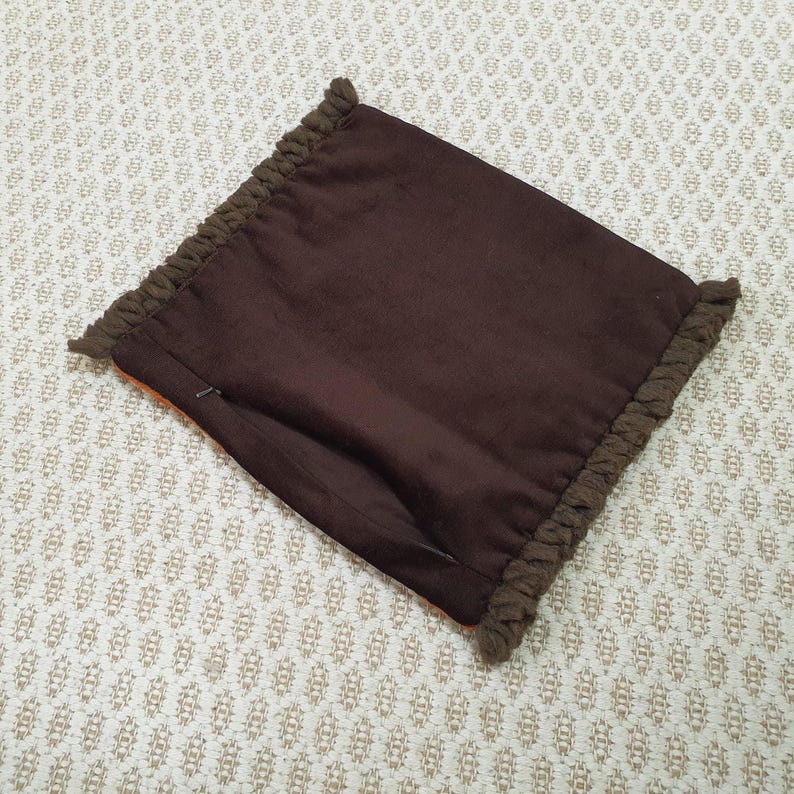 Puede incluir: Una funda de almohada marr&oacute;n con un borde texturizado y con flecos. La funda de almohada tiene una cremallera oculta y est&aacute; hecha de una tela marr&oacute;n oscuro lisa. El borde con flecos es de un tono marr&oacute;n m&aacute;s oscuro.